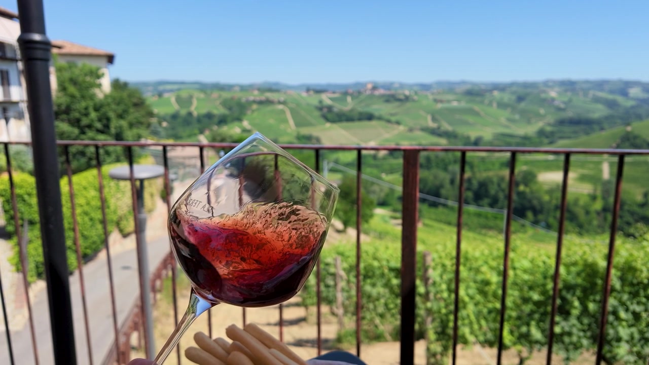 Verre de vin rouge tourbillonnant surplombant des vignobles italiens