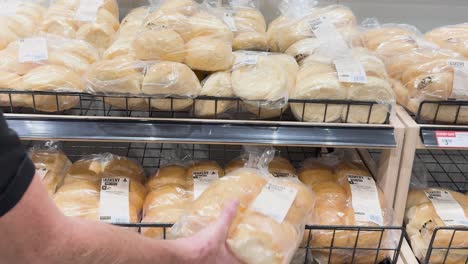 person choosing packaged bread rolls from shelf