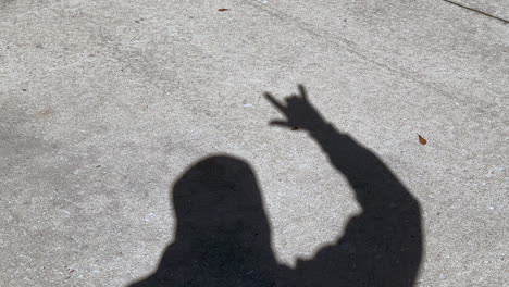 shadow of man waving rock and roll and rock on sign with fingers on hand