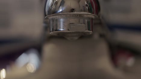 Close-up-water-droplets-fall-from-a-sink-faucet