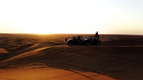 Toma-Aérea-De-Personas-Y-Vehículos-Buggy-En-Dunas-De-Arena-Al-Atardecer