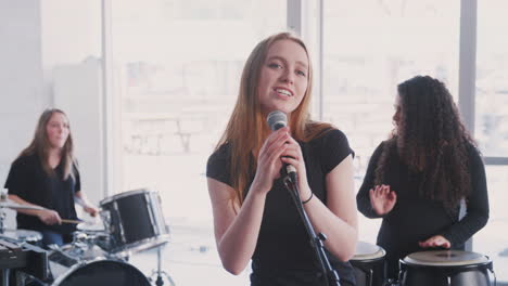 female students at performing arts school playing in band at rehearsal