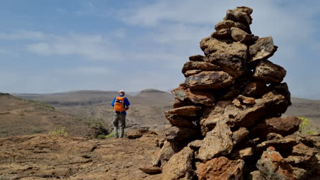 Hombre-Caminando-Y-En-Primer-Plano-Hay-Un-Montículo-De-Piedras