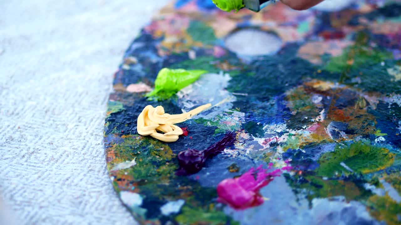 close-up, Art palette. The artist squeezes some green paint from a tube. there is a creative process. artist paints in nature