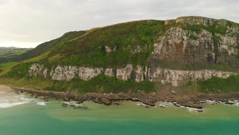 Left-to-right-panning-shot-during-the-day-of-the-side-of-a-cliff-by-the-coast-in-New-Zealand