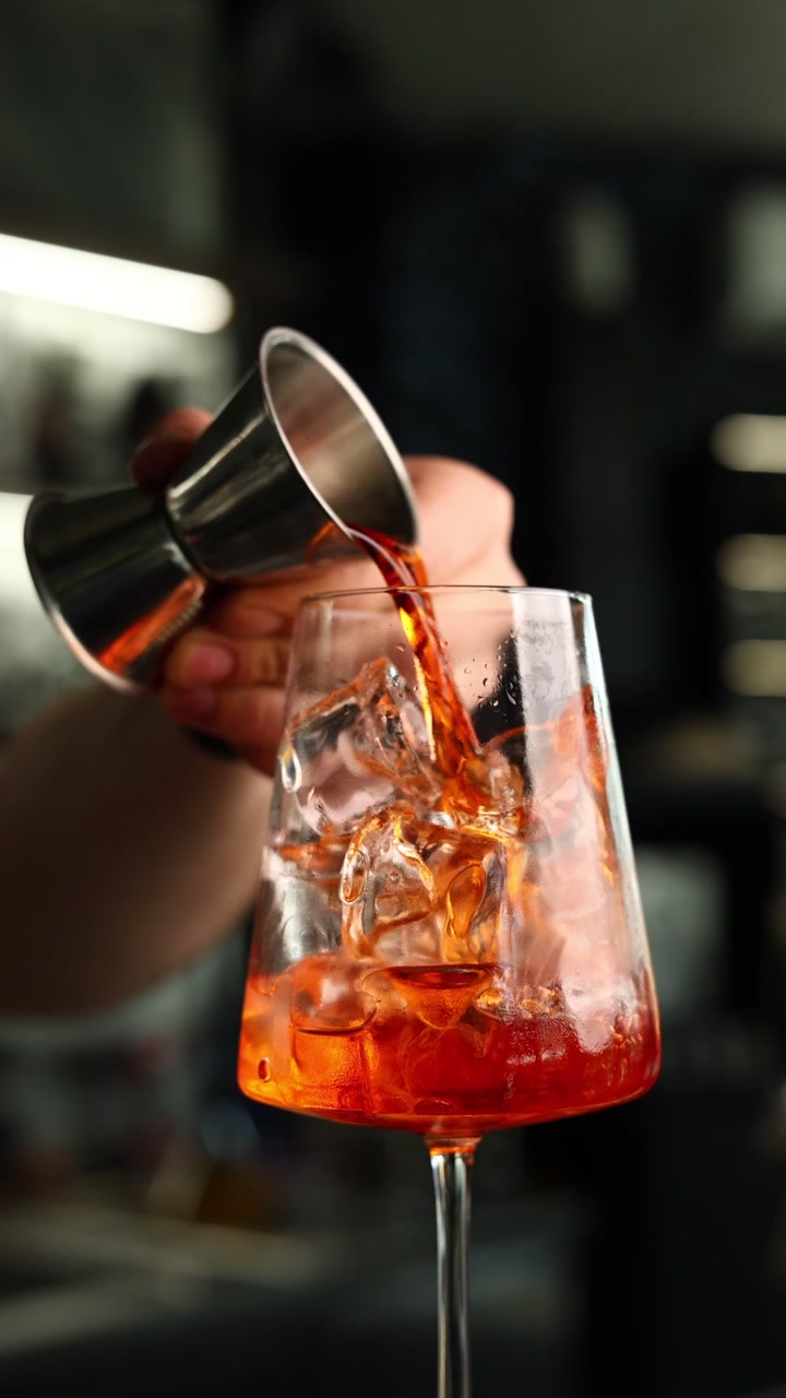 Barman che versa Aperol in un bicchiere con ghiaccio