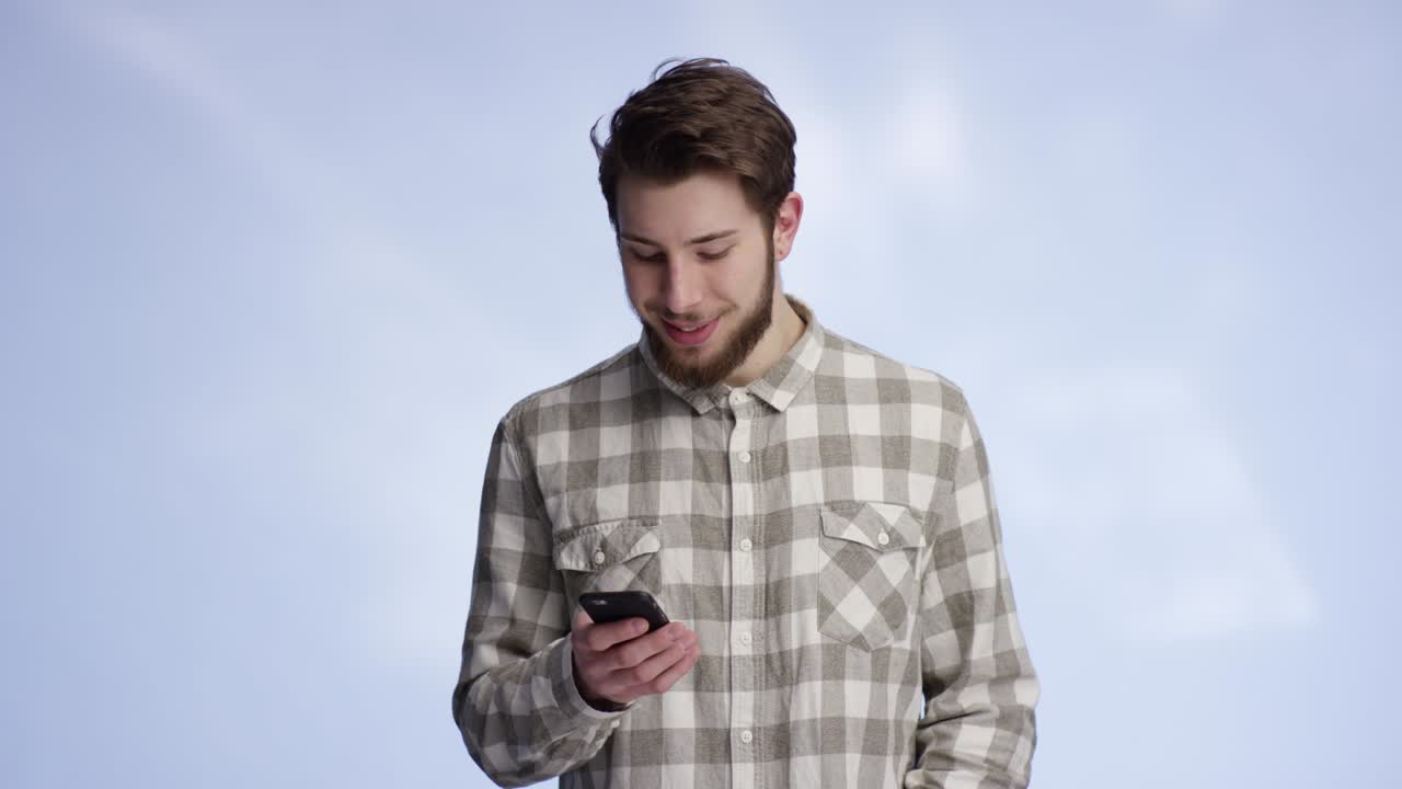 젊고 잘생긴 남자가 드폰으로 타이핑을 하고 카메라로 미소를 지었습니다.