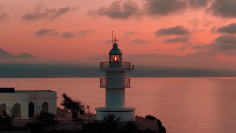 beautiful lighthouse on the mediterranean sea with mountains on background shot on sunrise