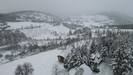 snowy mountain aerial panoramic shot with wooden cabin and forest covered with snow