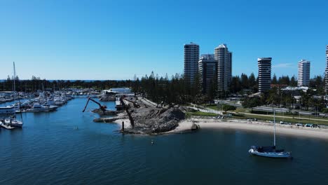 revealing drone view of a government infrastructure project in a boating marina and harbor next to a towering city skyline