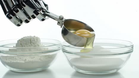 a robotic hand is seen precisely measuring flour with a metal scoop above two clear bowls filled with different white powders, showcasing advanced culinary technology in action.