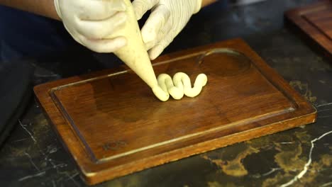 Up-close-chef-with-gloves-on-making-snake-shape-with-white-sauce