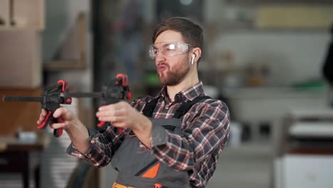 cute young man in work uniform shoots with a tool