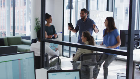 Diverse-group-of-happy-work-colleagues-talking-at-casual-office-meeting