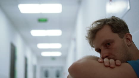 portrait exhausted physician staying alone in corridor. medical worker resting