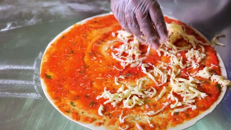 agregando queso fresco sobre salsa de pizza sobre masa de pizza