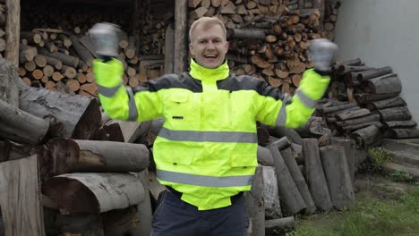 holzfäller in reflektierender jacke. mann holzfäller tanzt, feiert. gesägte stämme, feuerholz hintergrund