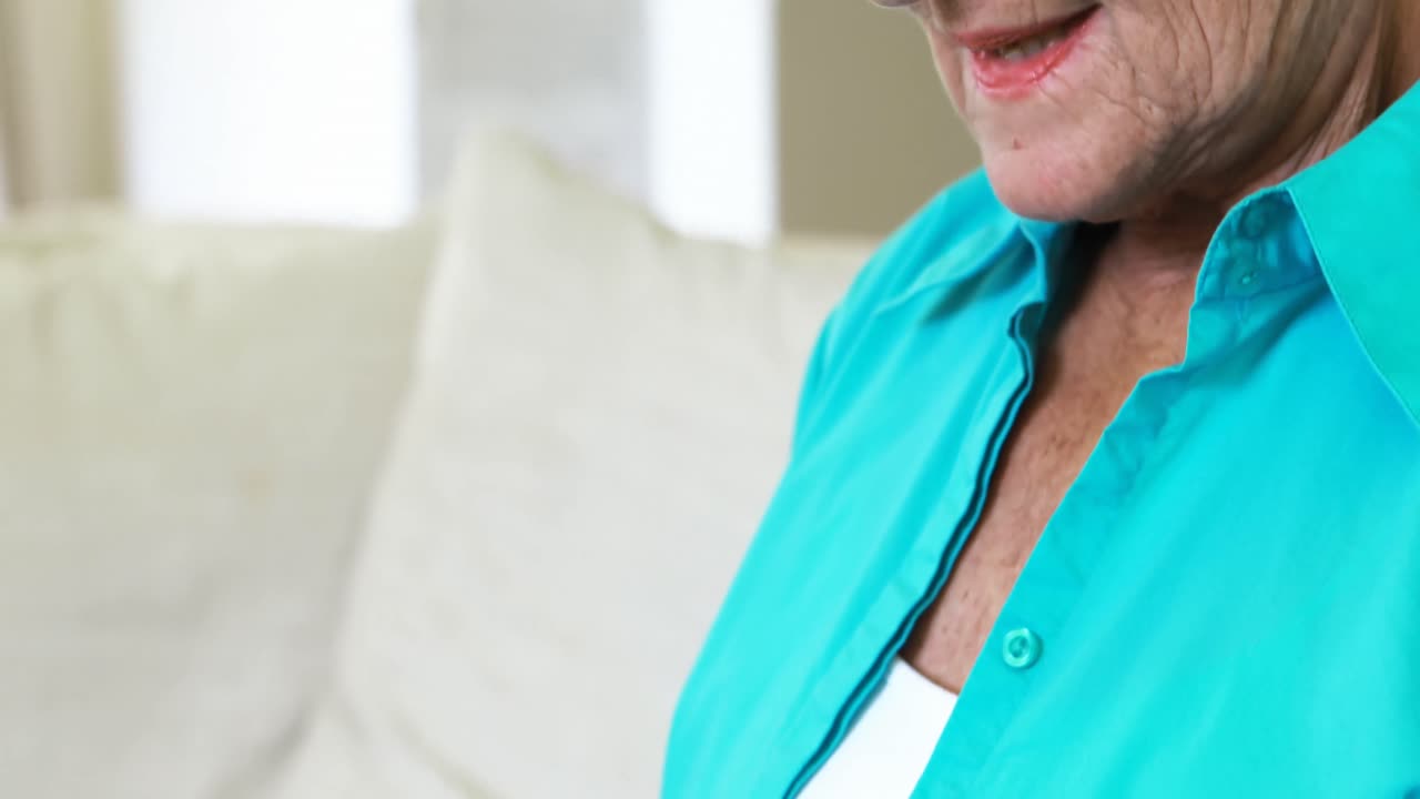 mujer mayor comprando en línea usando computadora portátil con tarjeta de crédito en la sala de estar