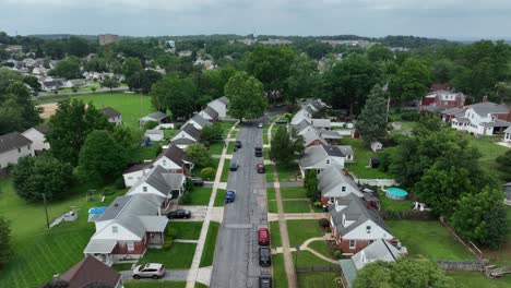 family friendly neighborhood in suburb during cloudy day. aerial birds eye. community with single family houses, semi-detached homes and multi-unit apartments in america. forward shot