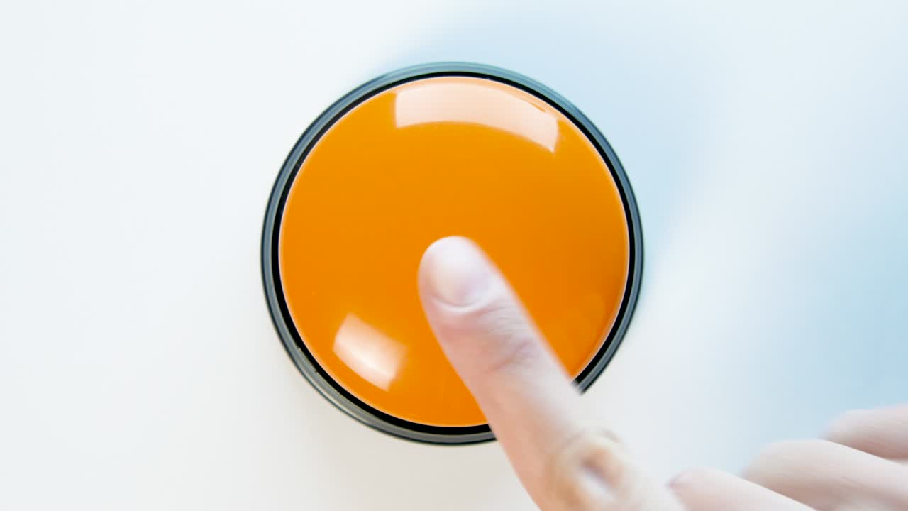 joven presionando el botón naranja con un dedo y la palma de la mano. presiona un botón redondo brillante, vista superior. activación, lanzamiento de algo. encender y apagar.