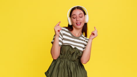 woman dancing with closed eyes listening to music in headphones expressing carefree joyful emotion