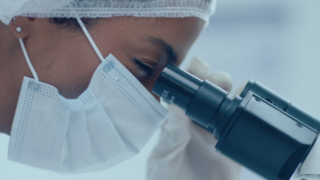 Female Scientist in Protective Mask and Gloves Using Microscope