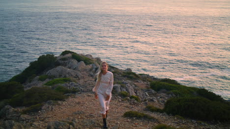 Preciosa-Modelo-Escalando-Un-Acantilado-Sola.-Mujer-Rubia-Para-Caminar-Colina-Agua-Horizonte