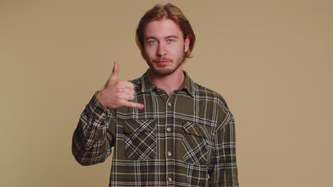 Cheerful-one-man-in-shirt-looking-at-camera-doing-phone-gesture-like-says-hey-you-call-me-back