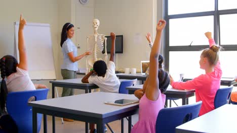 Schulkinder-Heben-Die-Hand,-Während-Sie-In-Der-Grundschule-Am-Schreibtisch-Sitzen,-4k