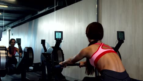 the pumped-up girl does exercises on the rowing machine