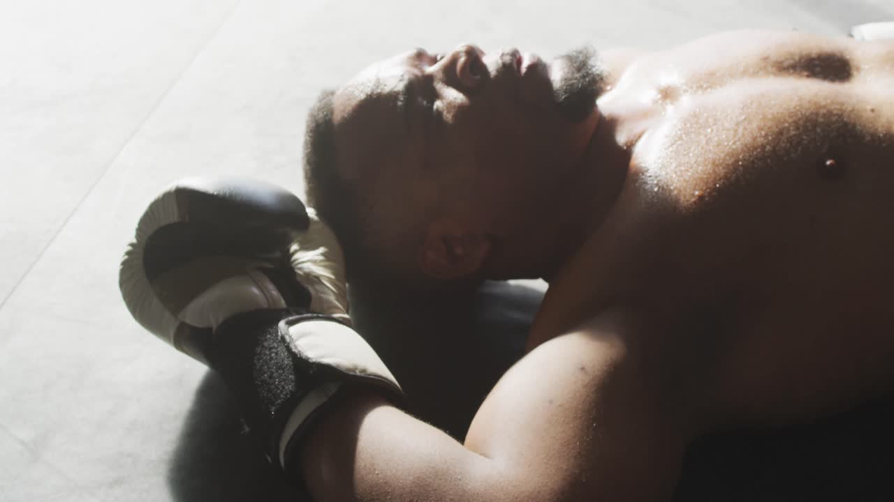 체육관 에서 박스 훈련 을 한 후 휴식 하는 피트 와 피곤 한 아프리카계 미국인 남자 의 영상