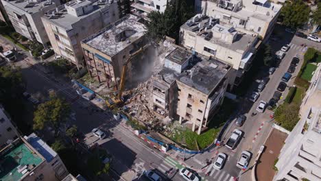 aerial orbit of building demolition using pincer claw attachment on hydraulic crane