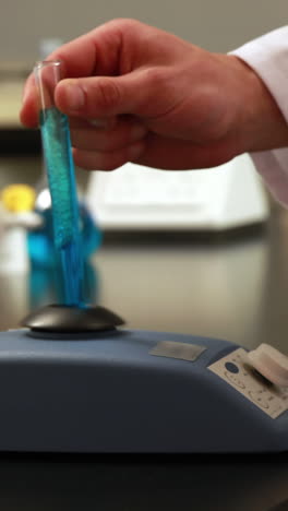 científico mezclando tubo de ensayo con centrifugadora