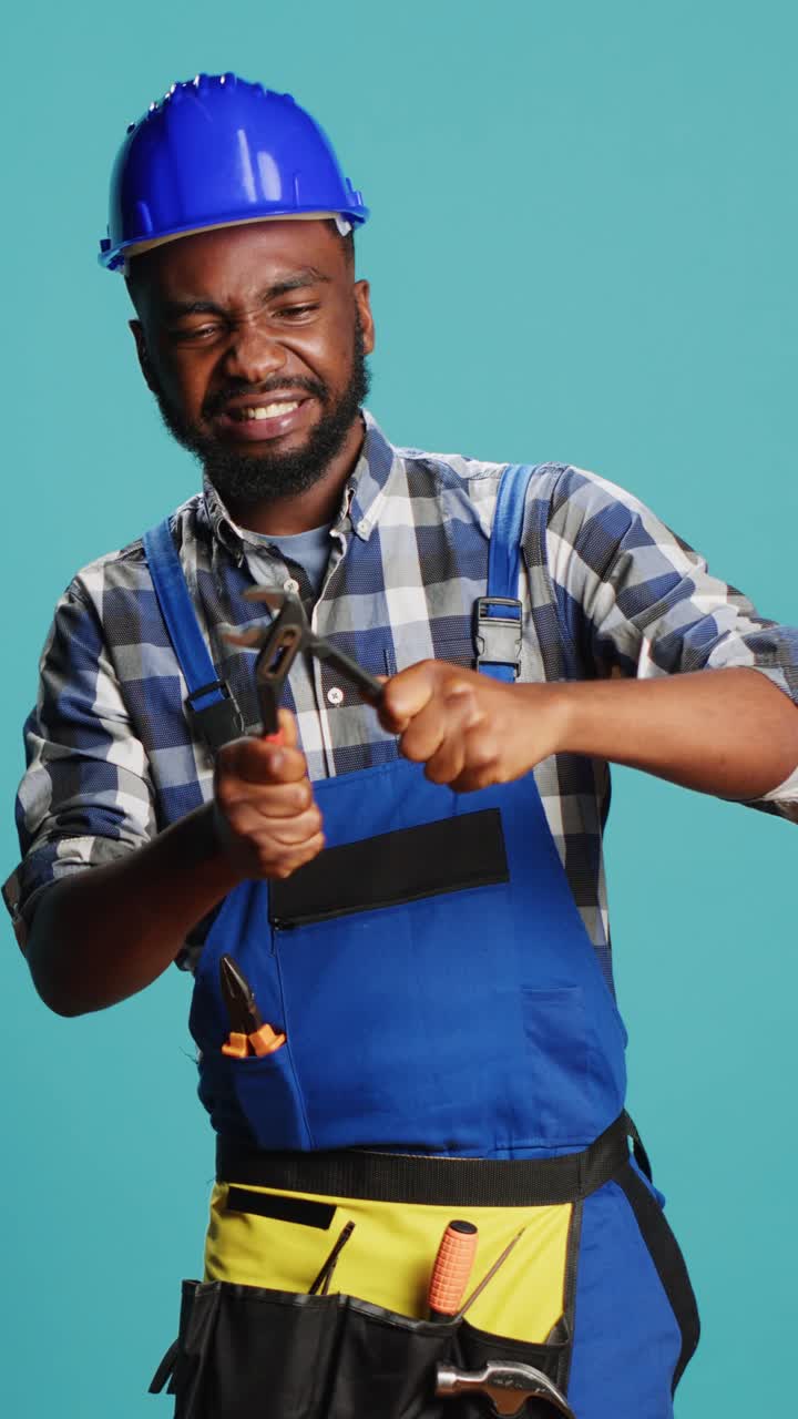 Vertical video: Young male carpenter tightening with spanner