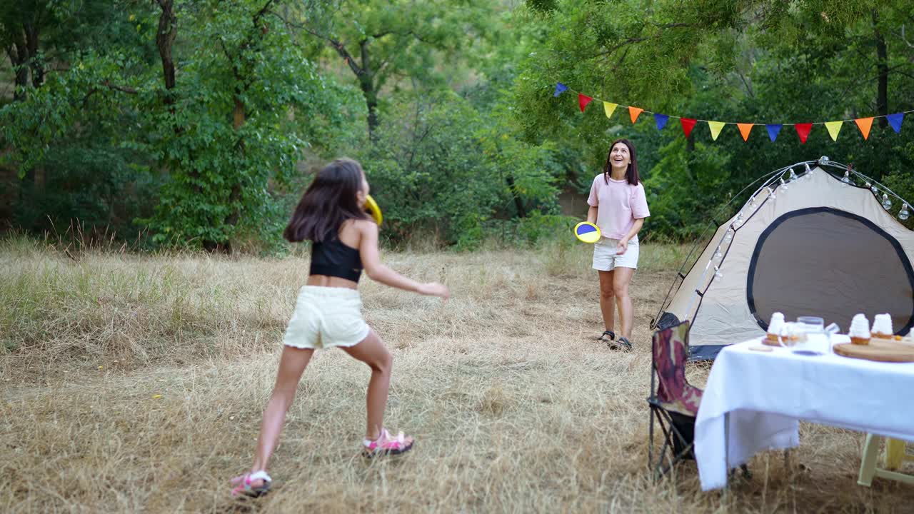 chicas jugando al frisbee en un picnic de campamento