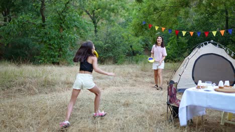 girls playing frisbee at a camping picnic