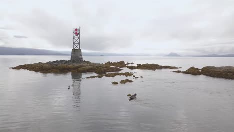 Close-up-Aerial-Orbit,-Vanderbilt-Reef-Harbour-Seals,-Cloudy,-Ominous-Clouds,-Navigation-Beacon