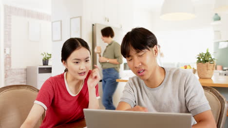 working together, asian brother and sister using laptop at home, concentrating on screen