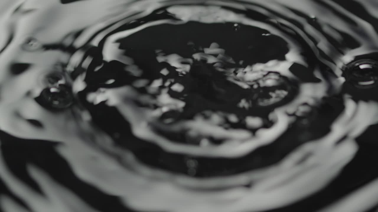 Gocce che colpiscono la superficie di un liquido creando bolle e cerchi concentrici di increspature