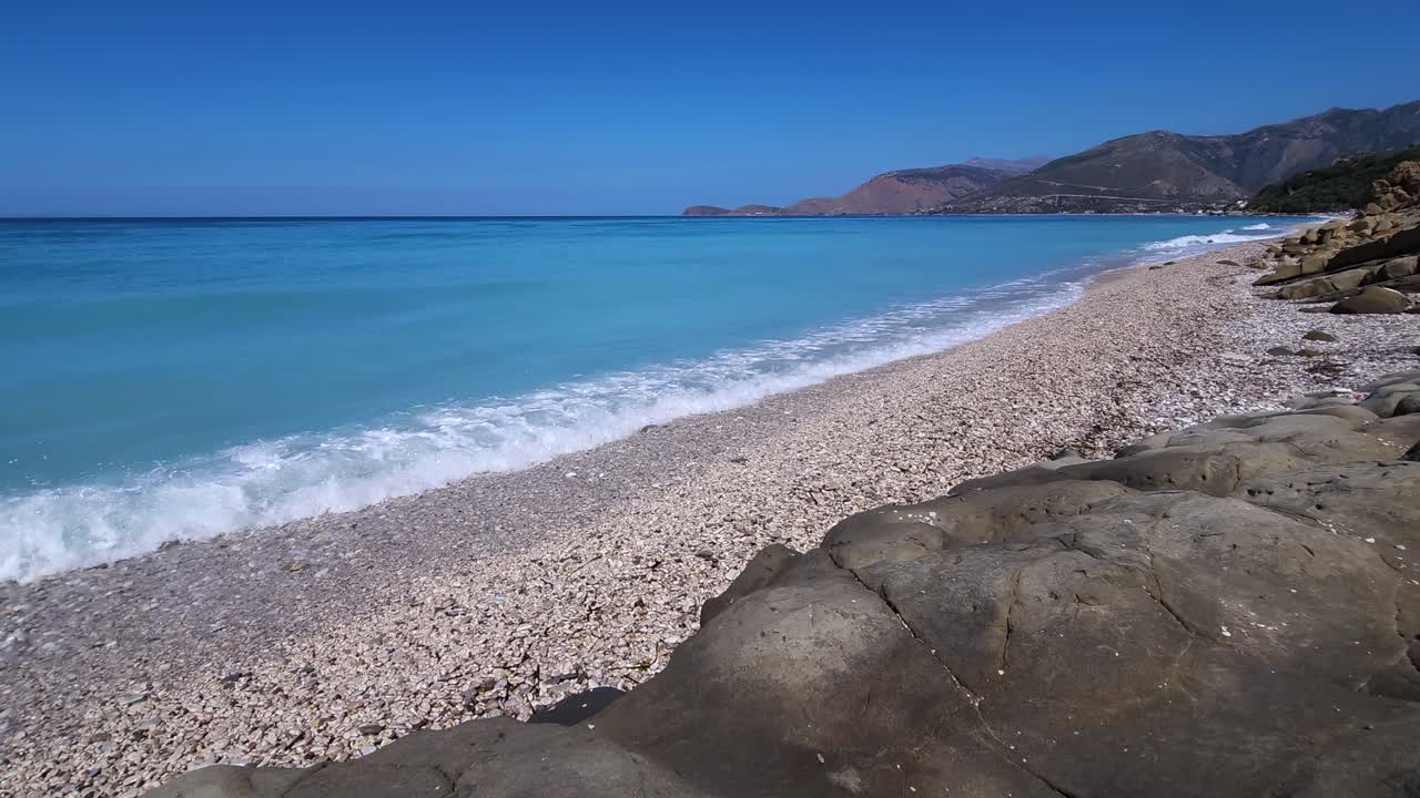 морские волны брызгают на пустом пляже с камешками, нет людей загорают на рассвете красивый красочный морской пейзаж на албанской ривьере