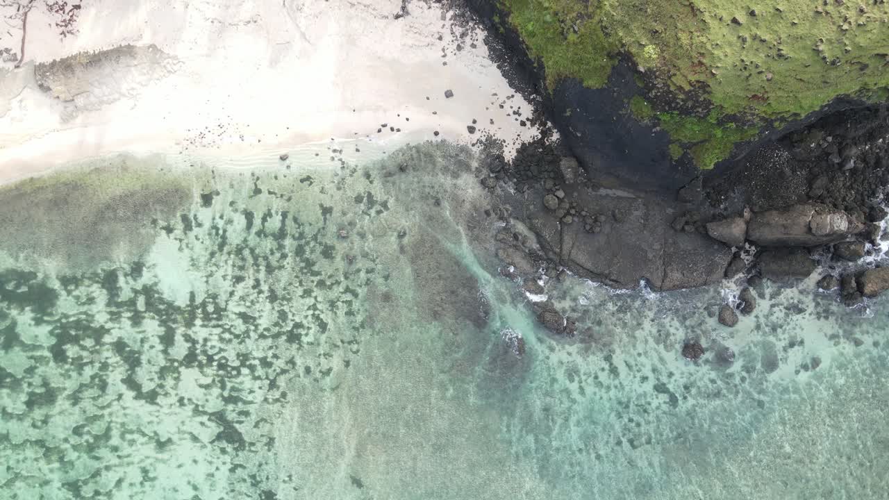 Luftfoto ovenfra af tropisk strand med klart turkist vand og klippekyst