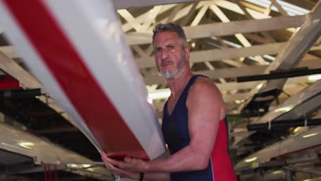 senior caucasian man carrying a rowing boat