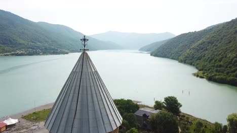 aerial past a beautiful castle and church on lake zhinvali in the republic of georgia