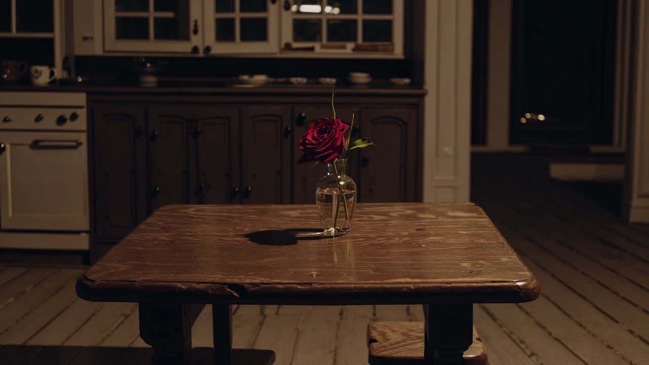 Single red rose resting in a glass vase, enhancing the rustic wooden table in a vintage kitchen, inviting warmth and charm into the cozy atmosphere of home decor