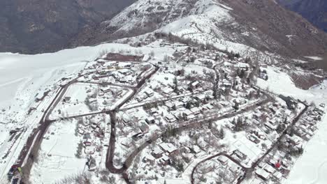 High-altitude-orbit-establishing-the-mountain-village-of-Farellones-full-of-snow,-ecosystem-friendly-streets-and-houses,-Chile