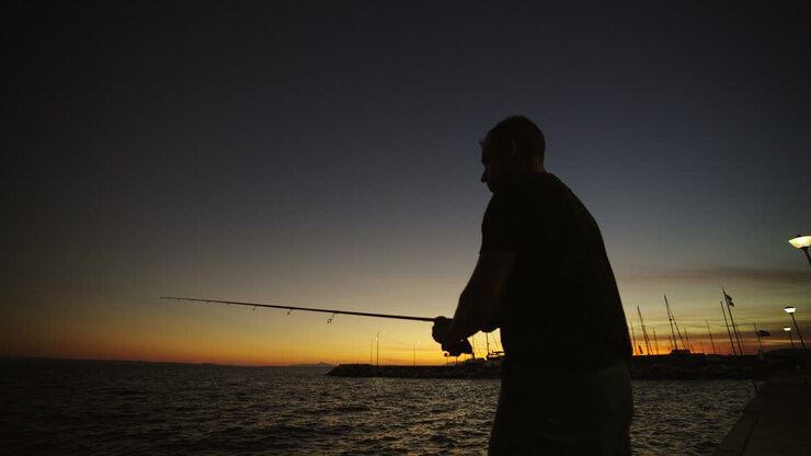 Silhouette of a Man Fishing at Sunset