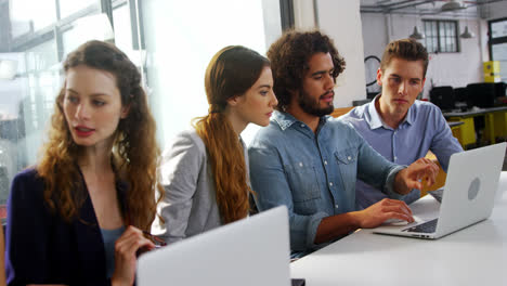 ejecutivos de negocios discutiendo sobre computadora portátil en una reunión