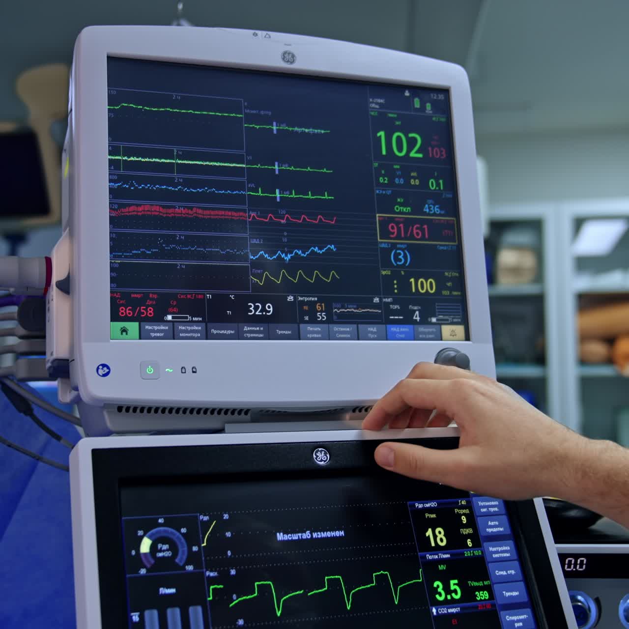 Male anesthesiologist pressing on the touch screen of lung ventilating machine. Doctor choosing the necessary parameters at operation
