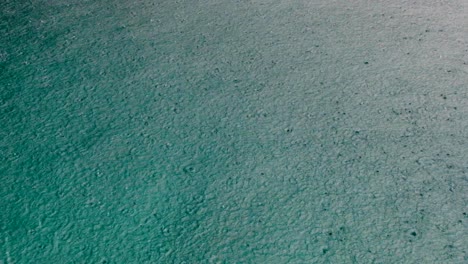 Close-up-of-raindrops-during-rain-downpour-onto-turquoise-ocean-water