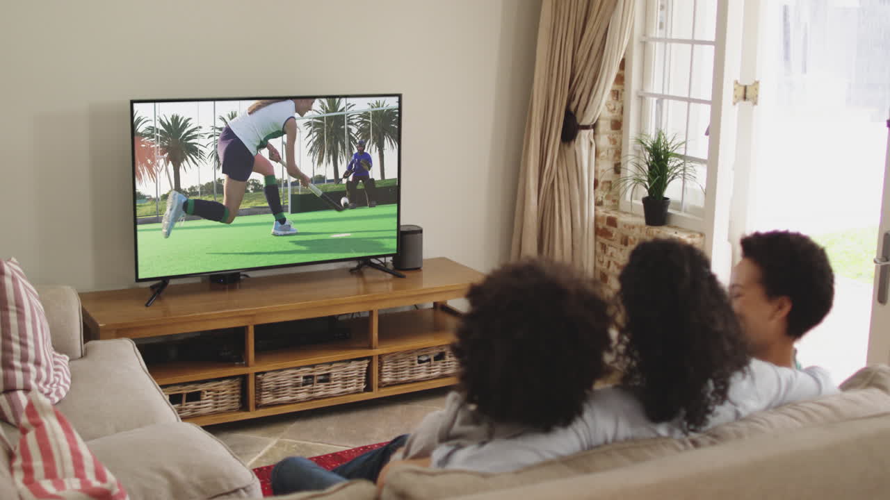 Famiglia felice seduta a casa insieme che guarda una partita di hockey in TV